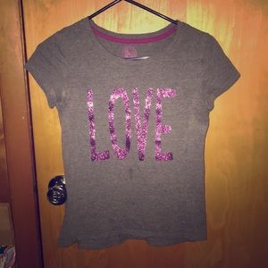 A gray shirt with the word “love” in glitter